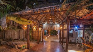 Ein Empfangsbereich mit einer Holzpergola, einer Rezeption und einem Weg zu einem Gebäude.