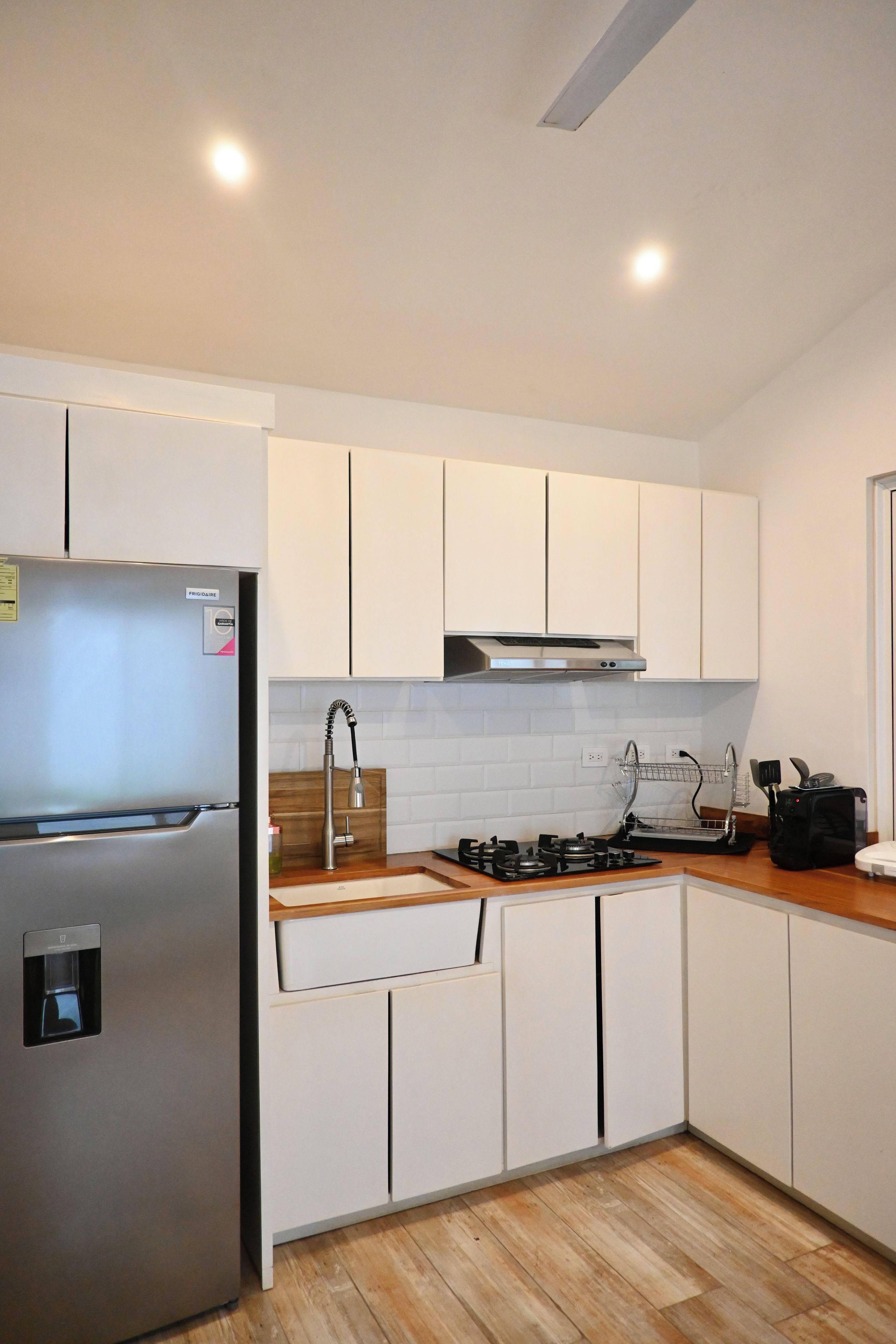 A modern kitchen with white cabinets, a stainless steel refrigerator, a gas stove, and a built-in oven.