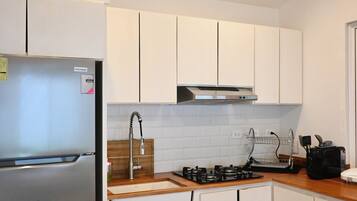 A modern kitchen with white cabinets, a stainless steel refrigerator, a gas stove, and a built-in oven.