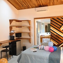 A bedroom with a bed, a desk, and a mirror.