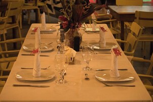 Una mesa de comedor dispuesta con platos, cubiertos y copas de vino, con un florero en el centro.
