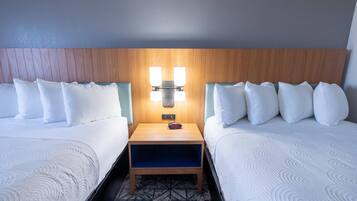Une chambre d’hôtel avec deux lits, une table de chevet avec une lampe et une moquette à motifs.