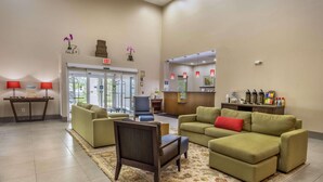 A lobby with a reception desk, green sofas, a patterned rug, and a chair.