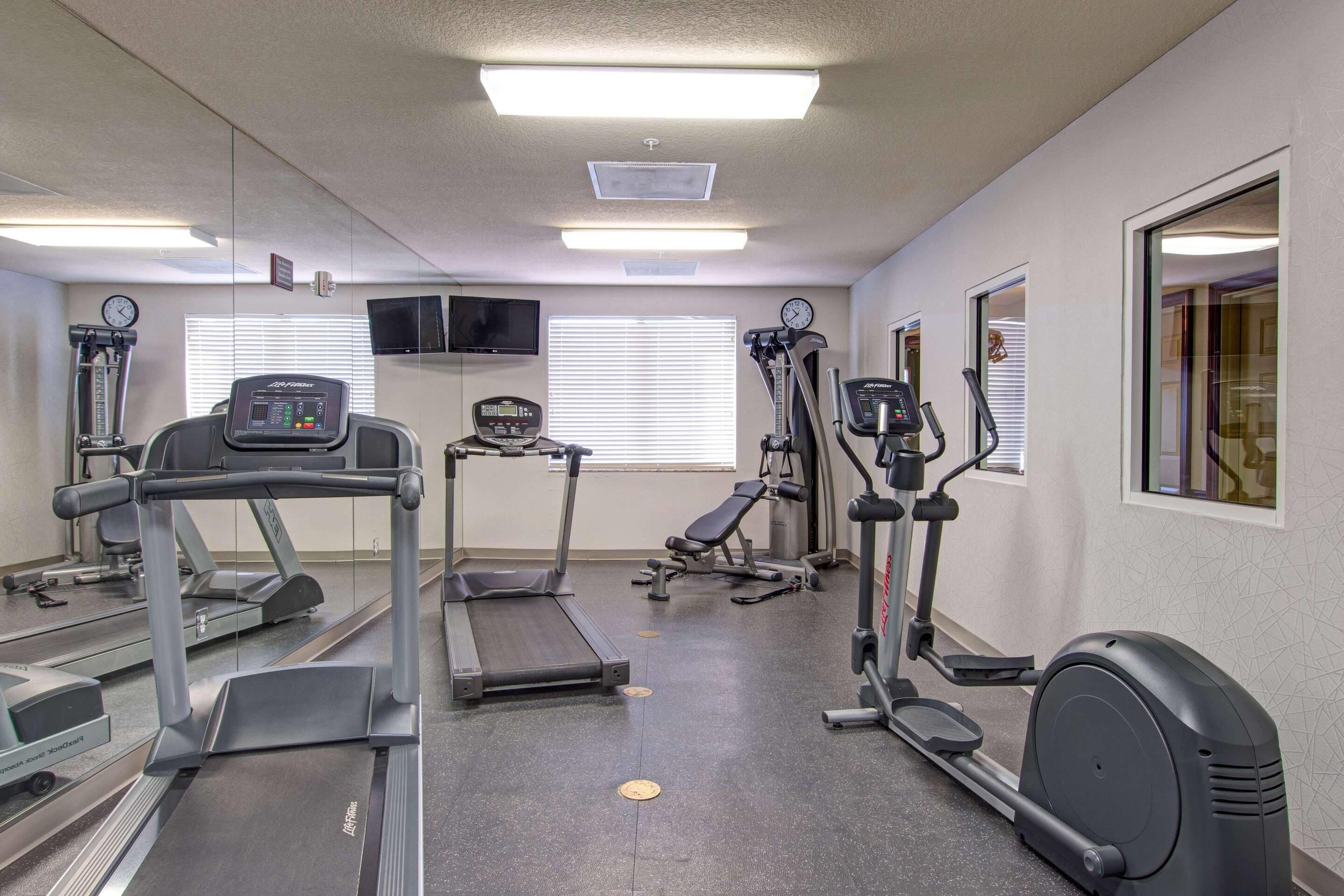 Un gimnasio con cintas de correr, elípticas y una banca.