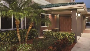 A modern building with a covered patio, brick walls, and a palm tree.