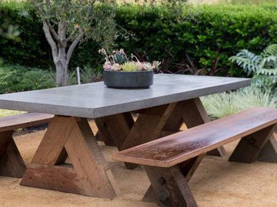 A wooden picnic table with benches, surrounded by greenery.
