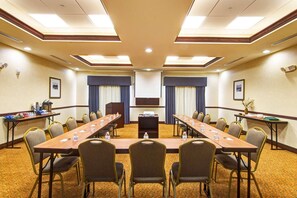 Una sala conferenze con un lungo tavolo, sedie, un leggio e uno schermo per proiezioni.