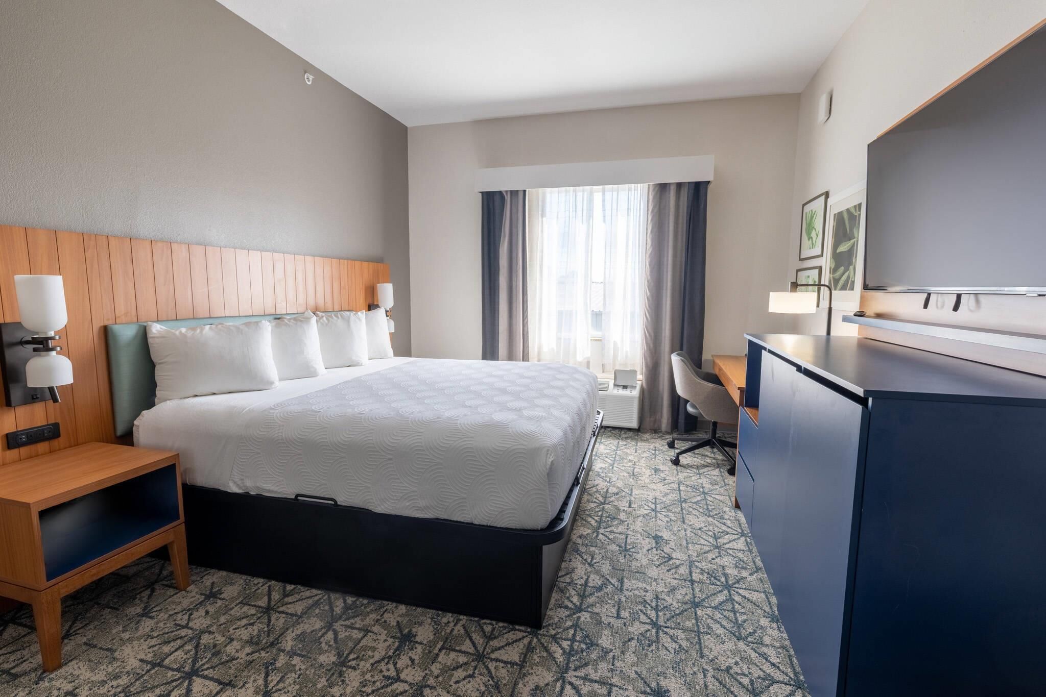 Une chambre d’hôtel équipée d’un lit, d’un bureau, d’une chaise et d’un téléviseur.