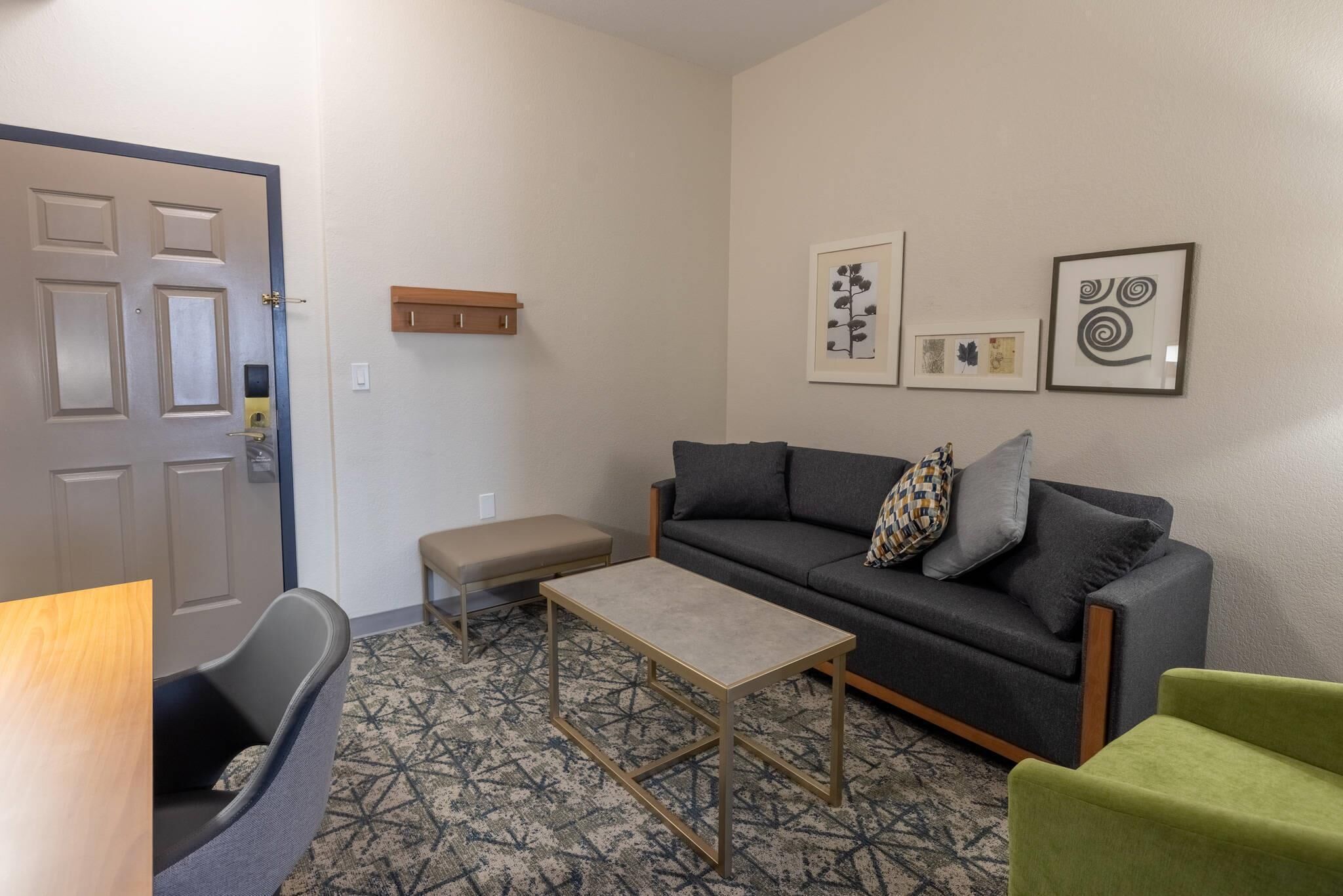 A living room with a sofa, a small table, a bench, and a door.