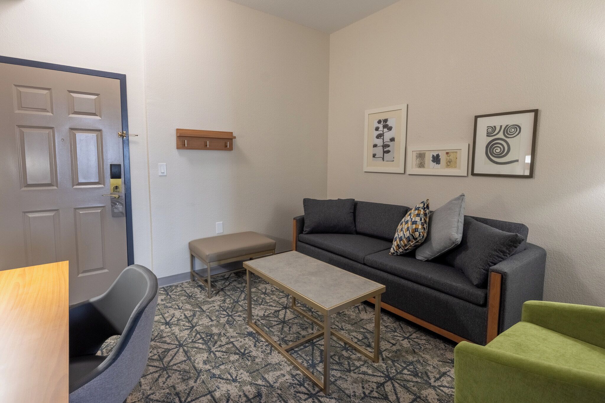 A room with a sofa, a small table, a bench, and a door.