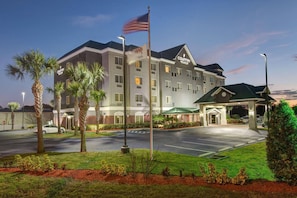 A multi-story hotel with a flagpole, a covered entrance, and a parking lot. - Country Inn & Suites by Radisson, St. Petersburg - Clearwater, FL (Pinellas Park)