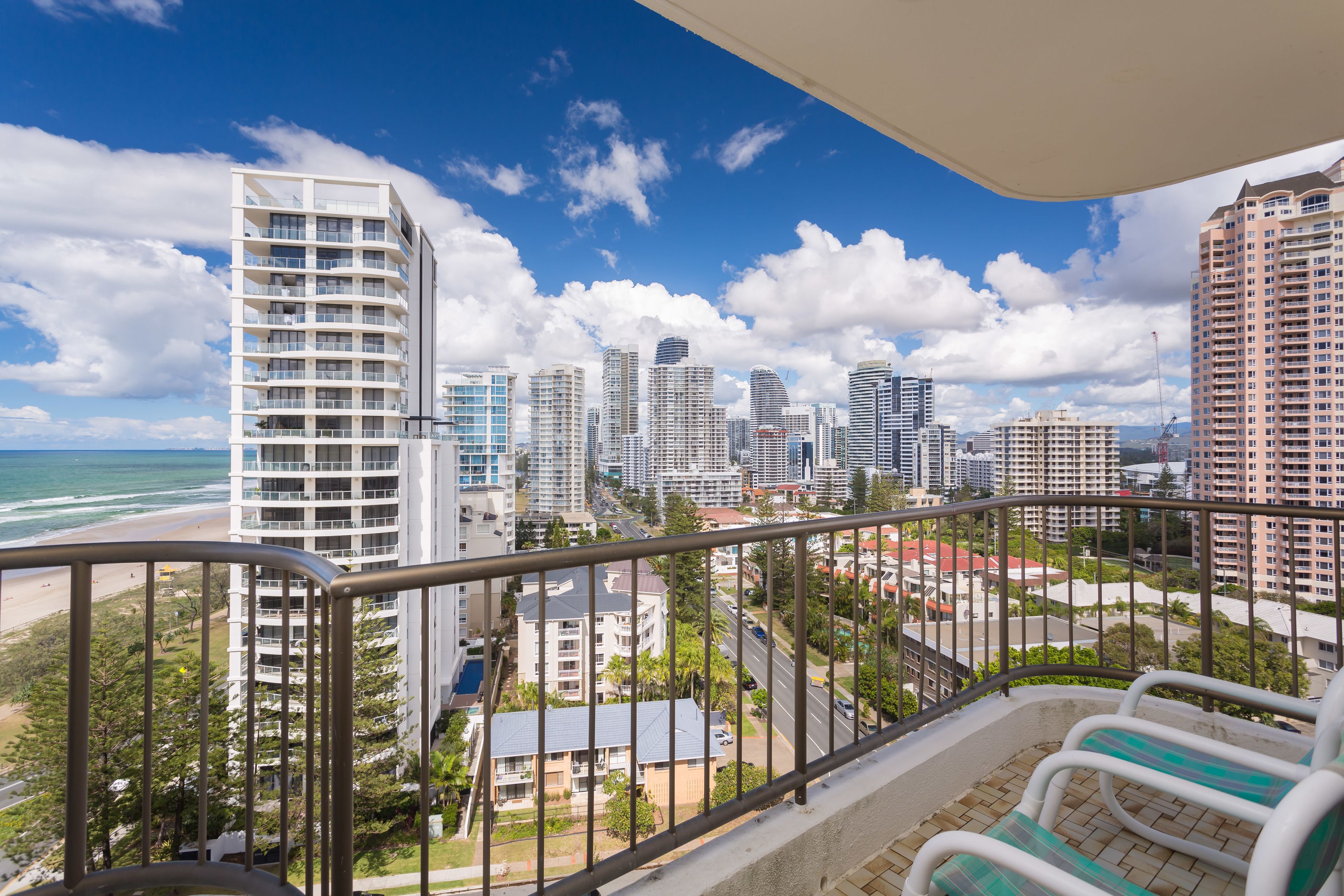 Un balcon offrant une vue sur le paysage urbain, avec notamment des immeubles de grande hauteur et une plage.