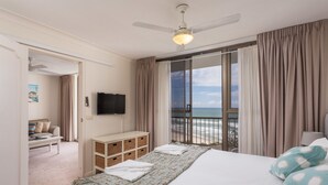Une chambre d’hôtel avec un lit, une télévision, un bureau et vue sur la plage.