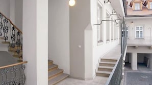 A modern interior with a staircase, a balcony, and a view of neighboring houses. - Prague Central Residence (Prague)