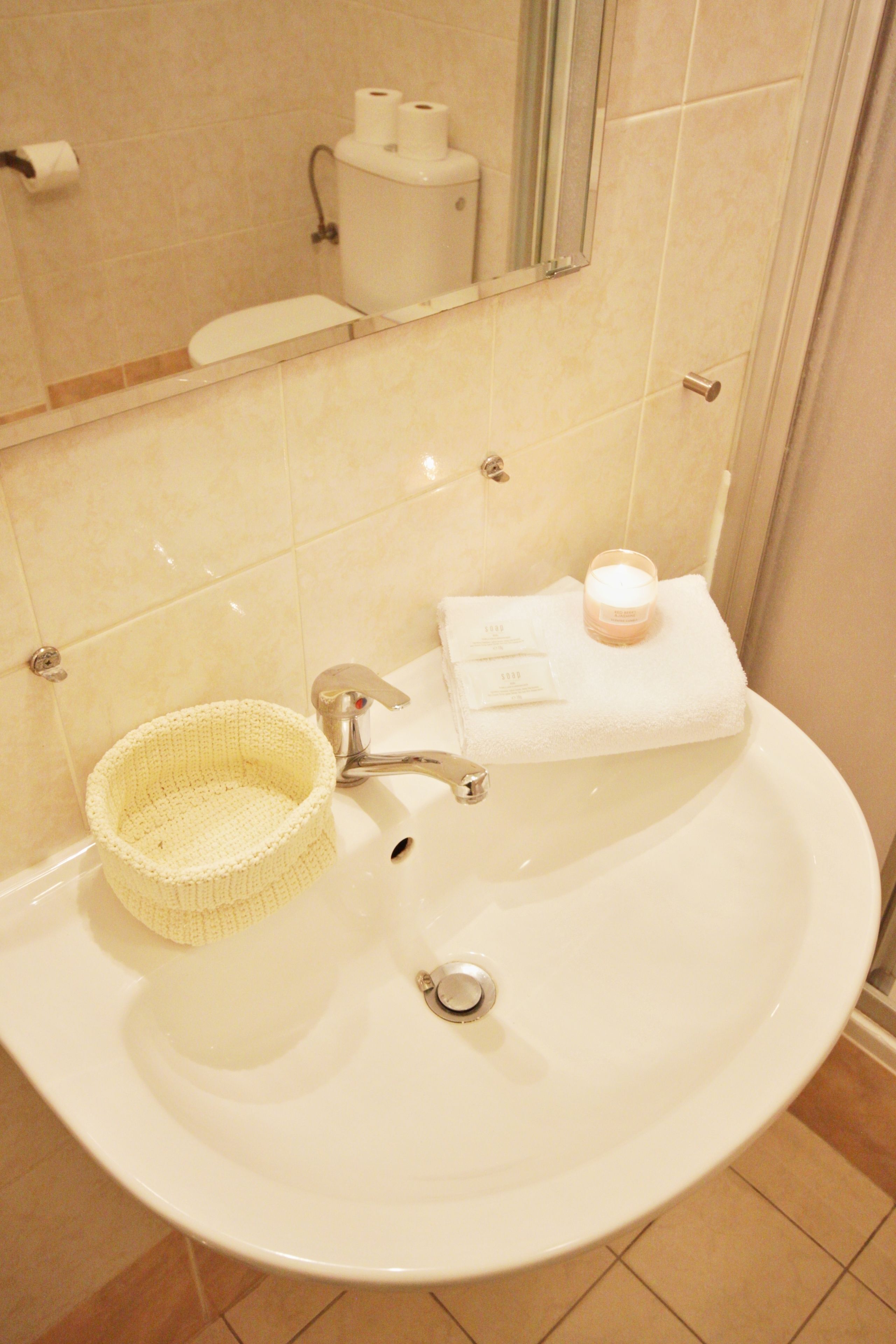 A bathroom with a sink, a mirror, a toilet, and a towel rack.
