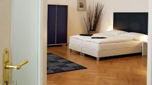 A bedroom with a bed, a wardrobe, a potted plant, and a door. - Prague Central Residence (Prague)
