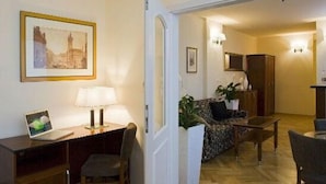 A hotel room with a desk, chair, lamp, sofa, and a dining area with a table and chairs. - Prague Central Residence (Prague)