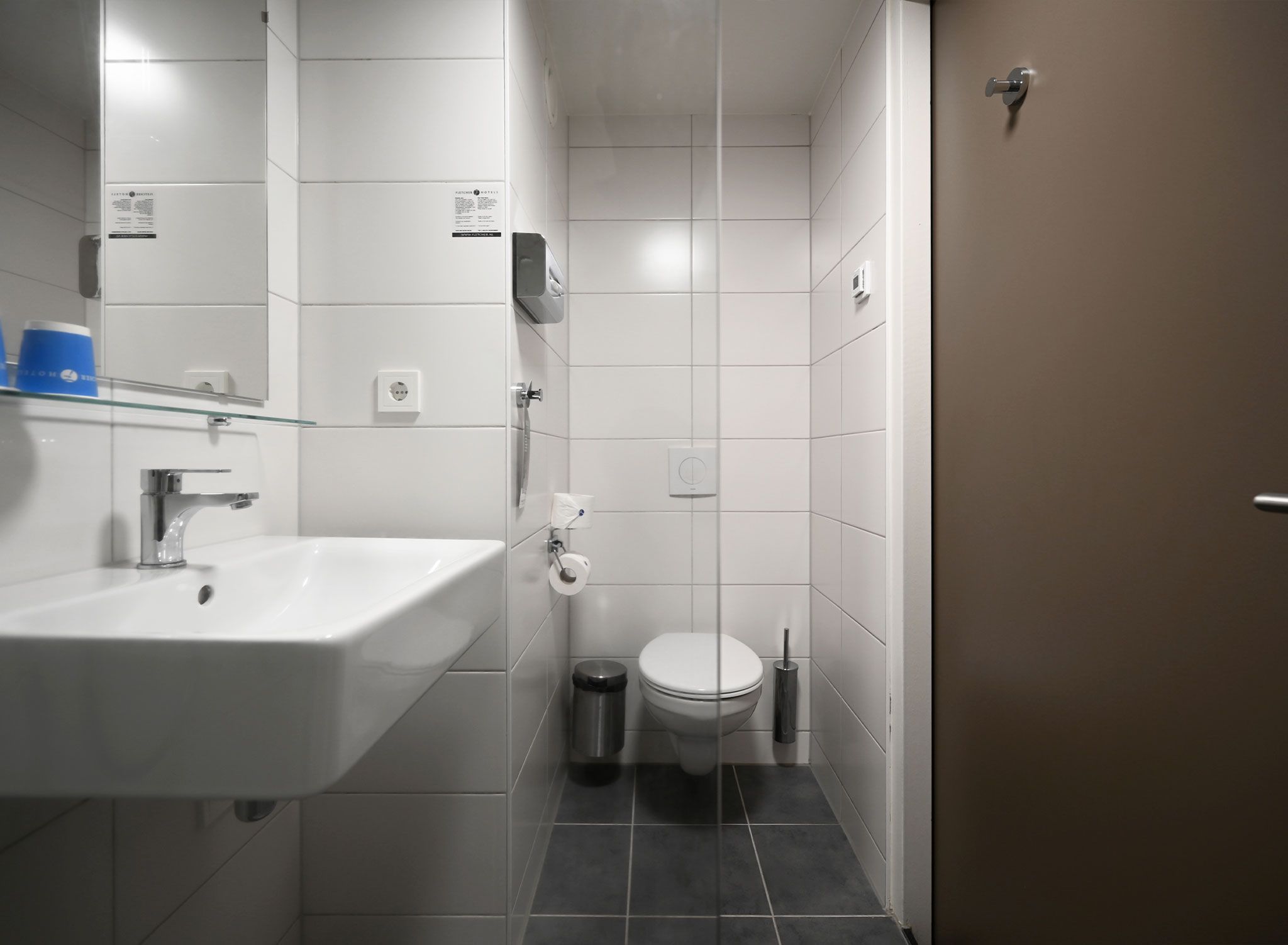 Un baño moderno con lavamanos blanco, inodoro y zona de ducha.