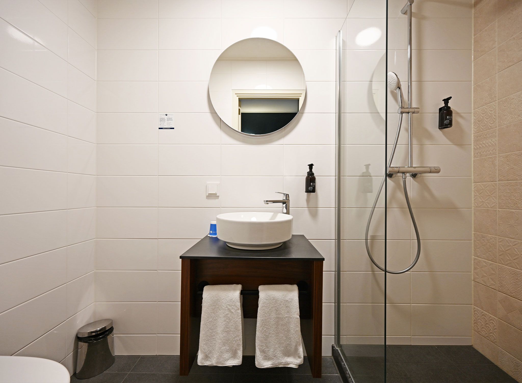 A modern bathroom with a round mirror, a sink, and a shower.