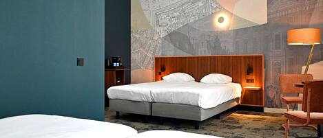Habitación de hotel con cama, mesita de noche, lámpara y un mural en la pared con vista urbana.