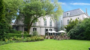 Un edificio grande e histórico con un jardín bien cuidado y un área de estar al aire libre.