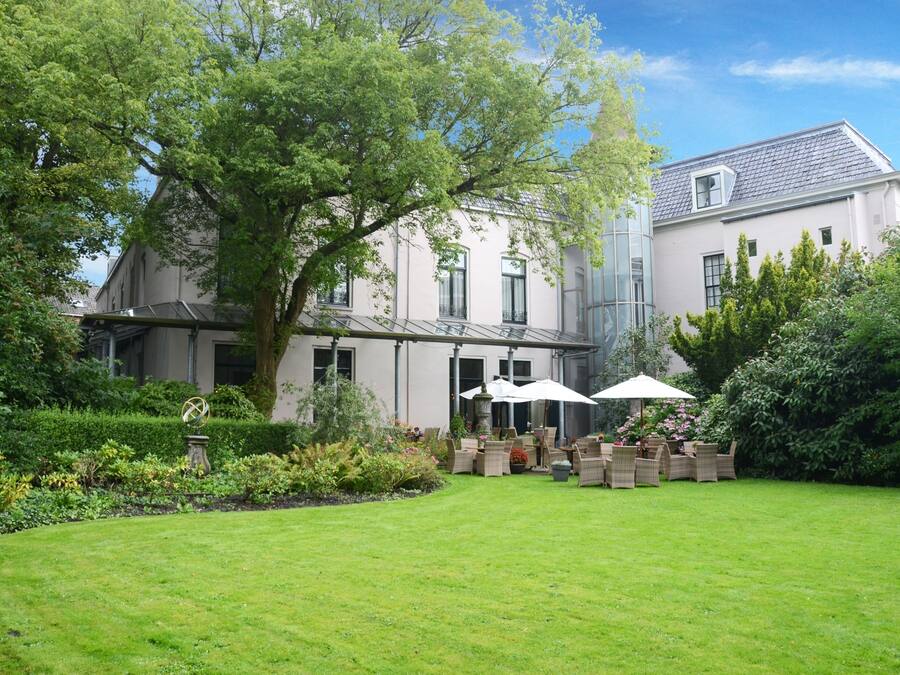 A large, historic building with a well-maintained garden and outdoor seating area.
