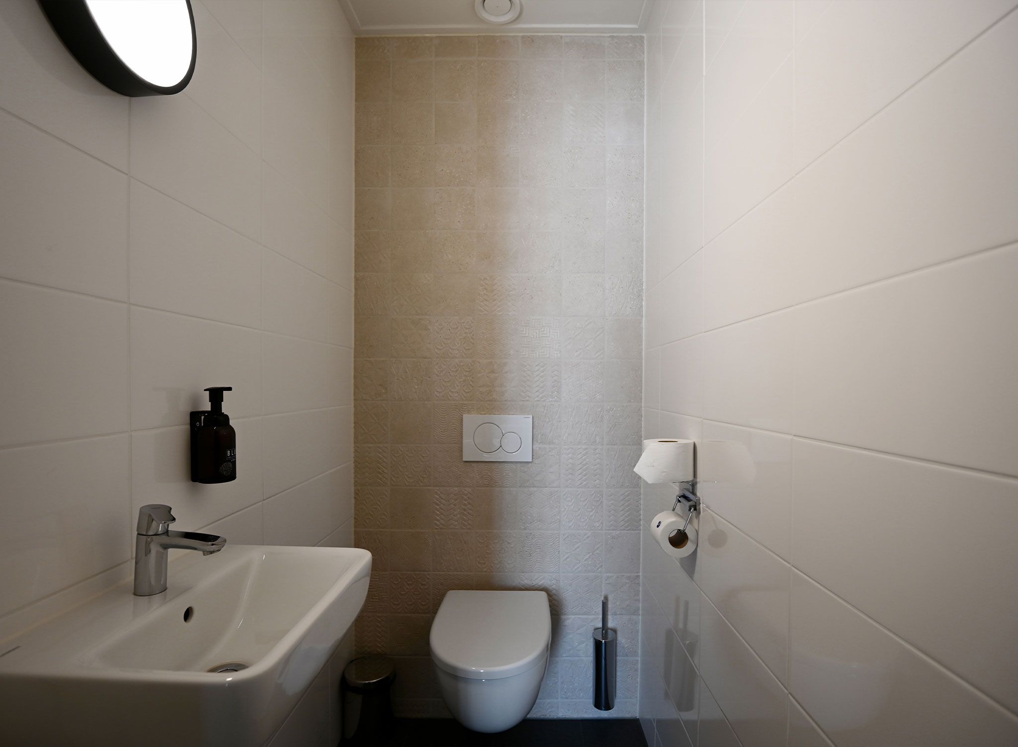 Un baño pequeño con lavamanos, inodoro y secador de manos.