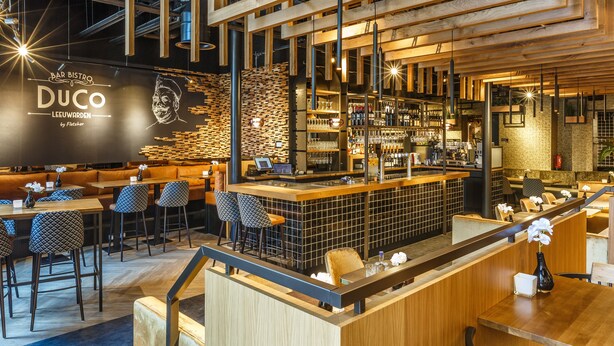 Un bar moderno y zona de estar con detalles de madera, una barra y un panel de menú.