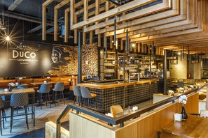 Un bar moderno y zona de estar con detalles de madera, una barra y un panel de menú.