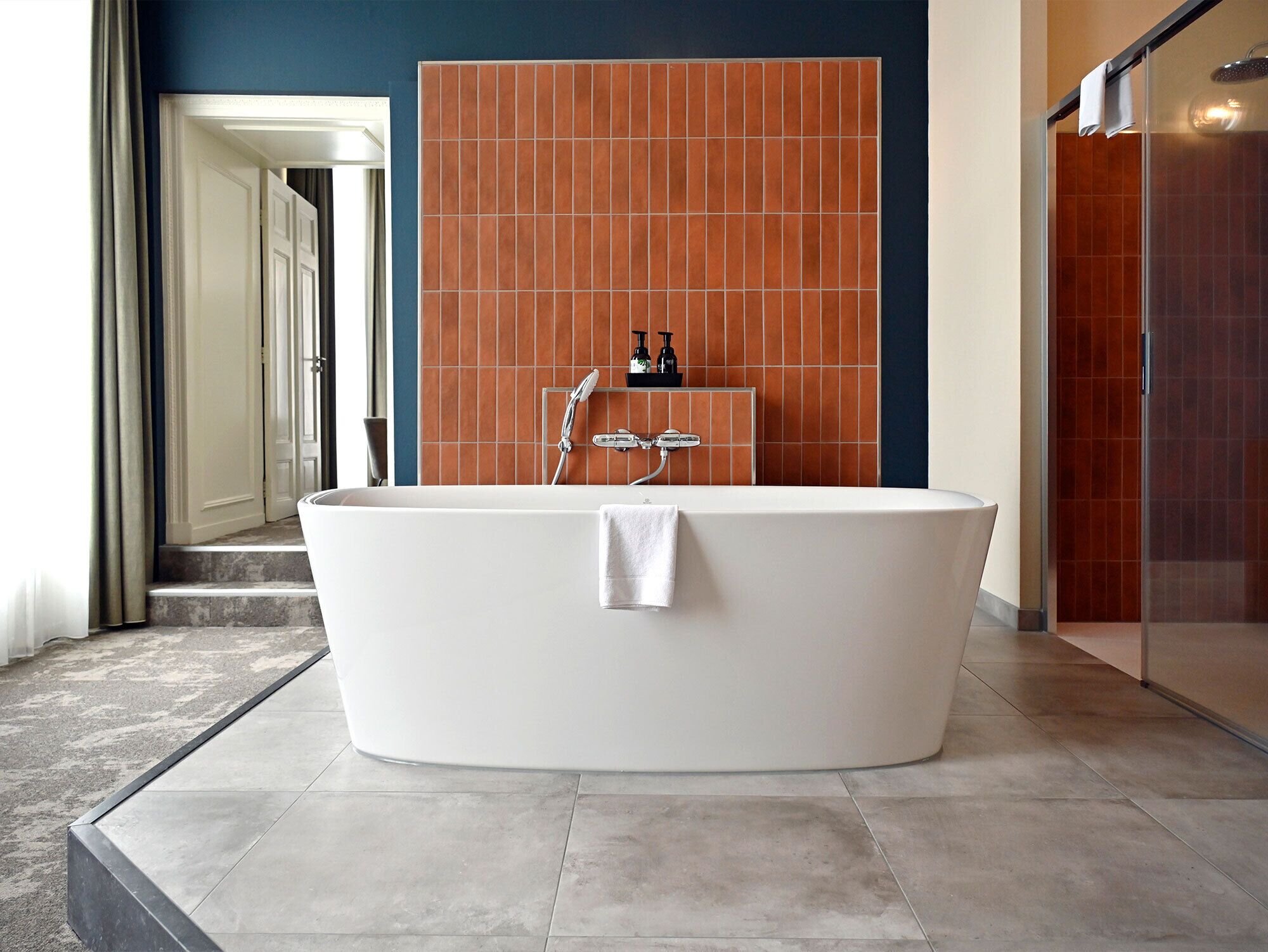 Un baño moderno con una bañera independiente, una zona de ducha y una pared con azulejos.