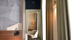 Habitación de hotel con cama, una silla, una lámpara y vista a otra habitación.