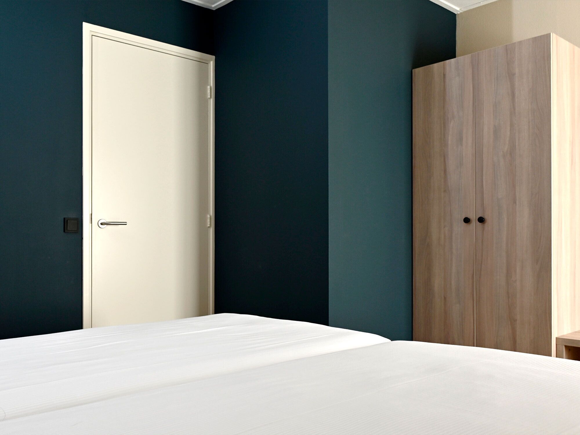 A bedroom with a bed, a wardrobe, and a door.