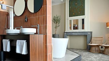 Une salle de bain avec deux lavabos, un grand miroir, une plante en pot et une cheminée.