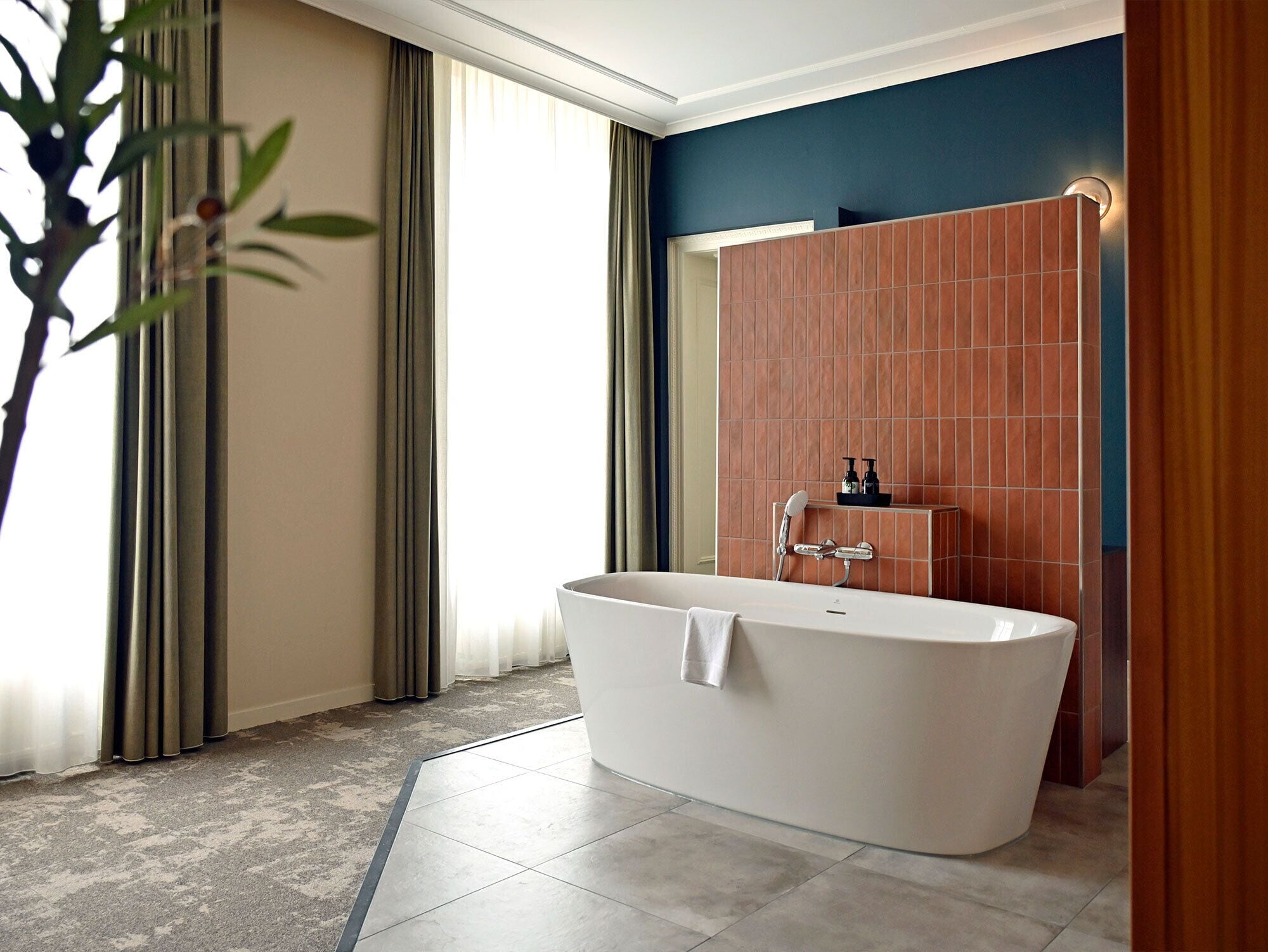 Une salle de bain moderne avec une baignoire sur pieds, un espace douche et une grande fenêtre avec des rideaux.