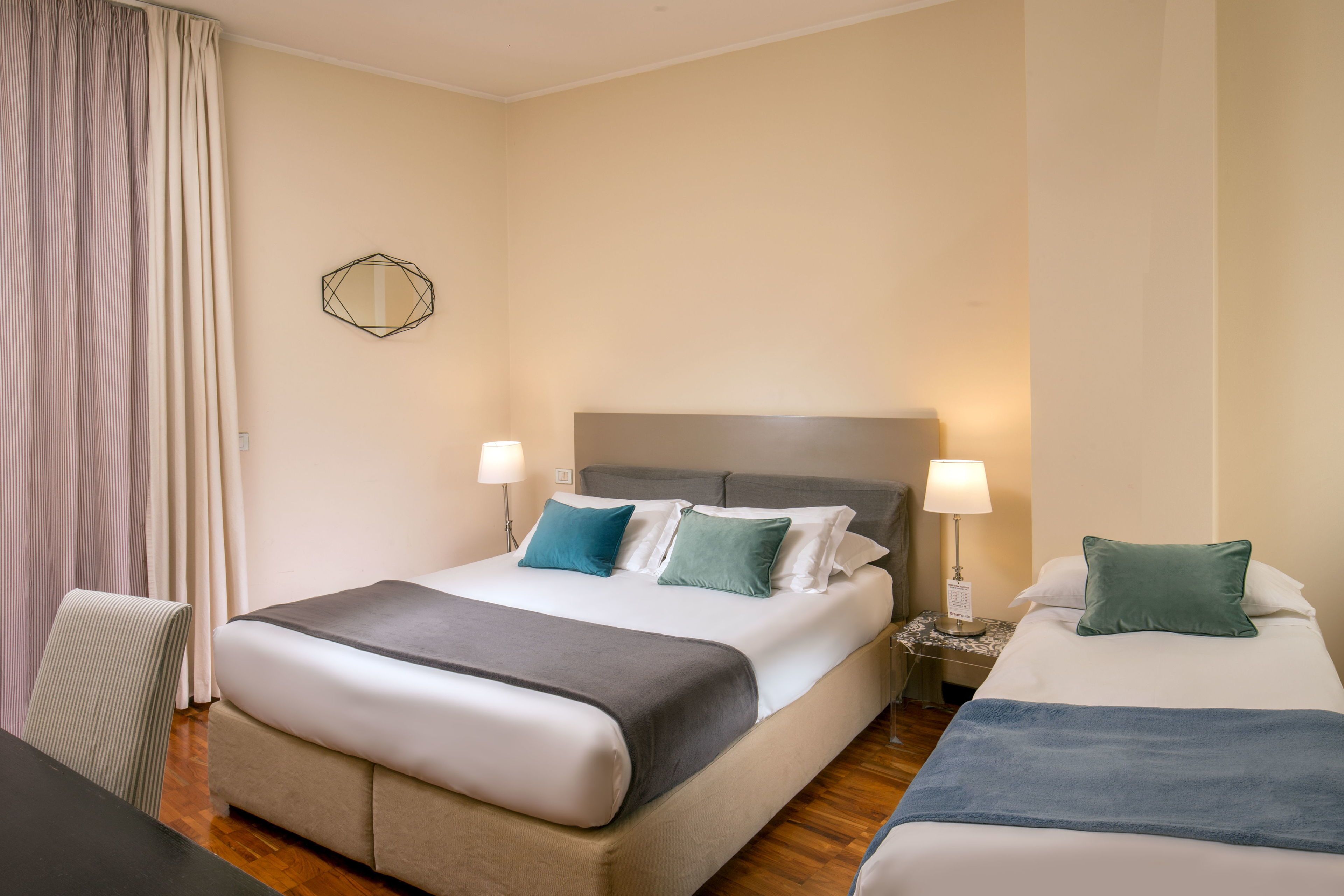 A hotel room with a large bed, two bedside tables, a chair, and a mirror on the wall.
