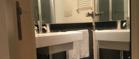 A bathroom with two sinks, a mirror, and a towel rack.