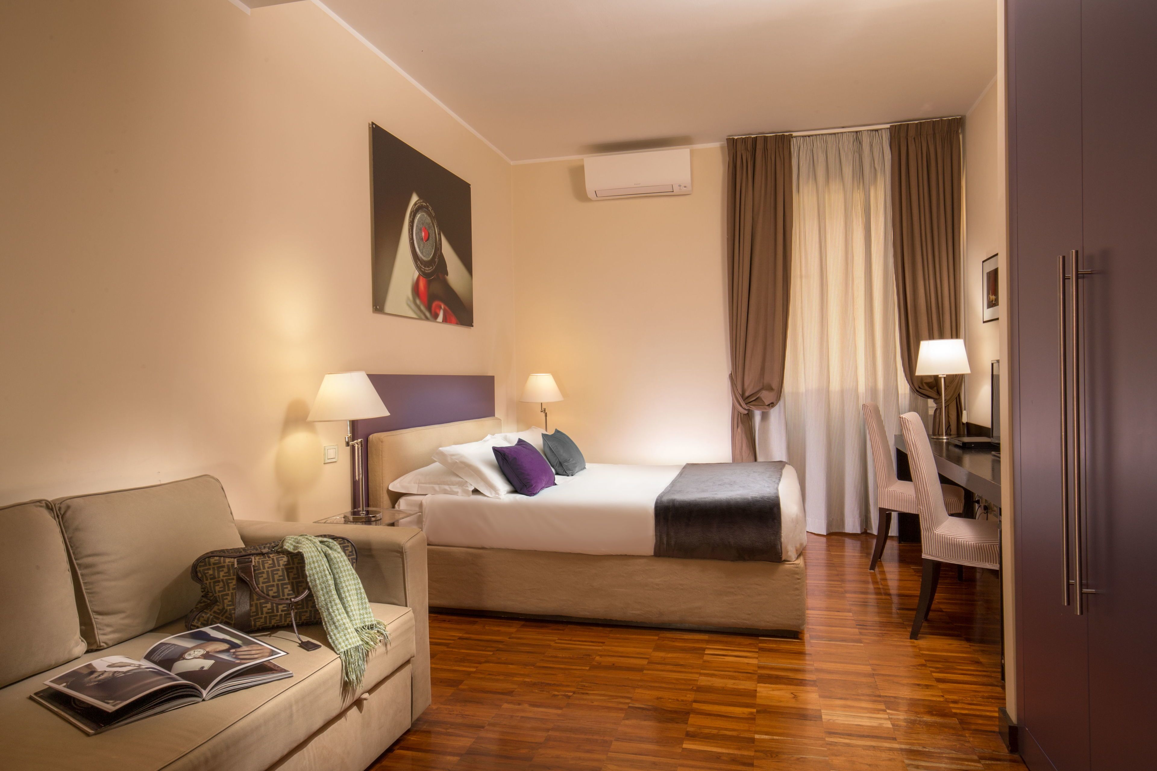 A hotel room with a bed, a sofa, a desk, and a chair.