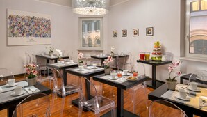 A dining area with transparent chairs, tables set with white plates, cups, and clear glassware. - Suitedreams (Rome)