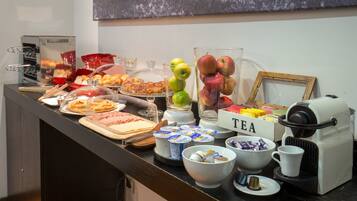 Ein Frühstücksbuffet mit verschiedenen Speisen, einer Teeausgabe und einer Kaffeemaschine.