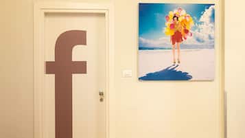 A door with a large Facebook logo and a painting of a person holding balloons on a beach.