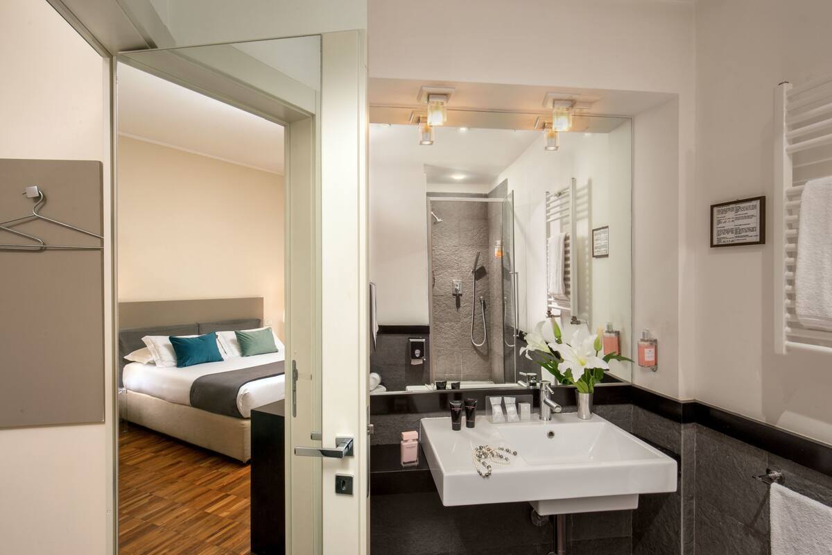 A modern bathroom with a large mirror, a white sink, and a shower area.