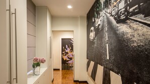 A hallway with a wooden floor, a white wall with a door, and a large black and white mural on the right. - Suitedreams (Rome)