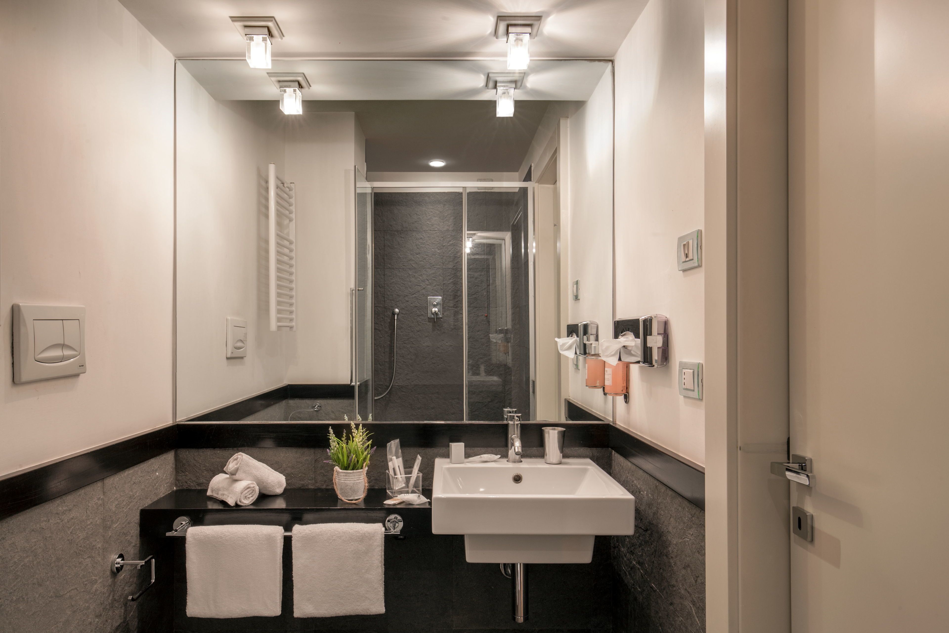 A modern bathroom with a black countertop, white sink, and a glass shower enclosure.