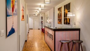 A hotel corridor with a reception desk, artwork on the walls, and a wooden floor. - Suitedreams (Rome)