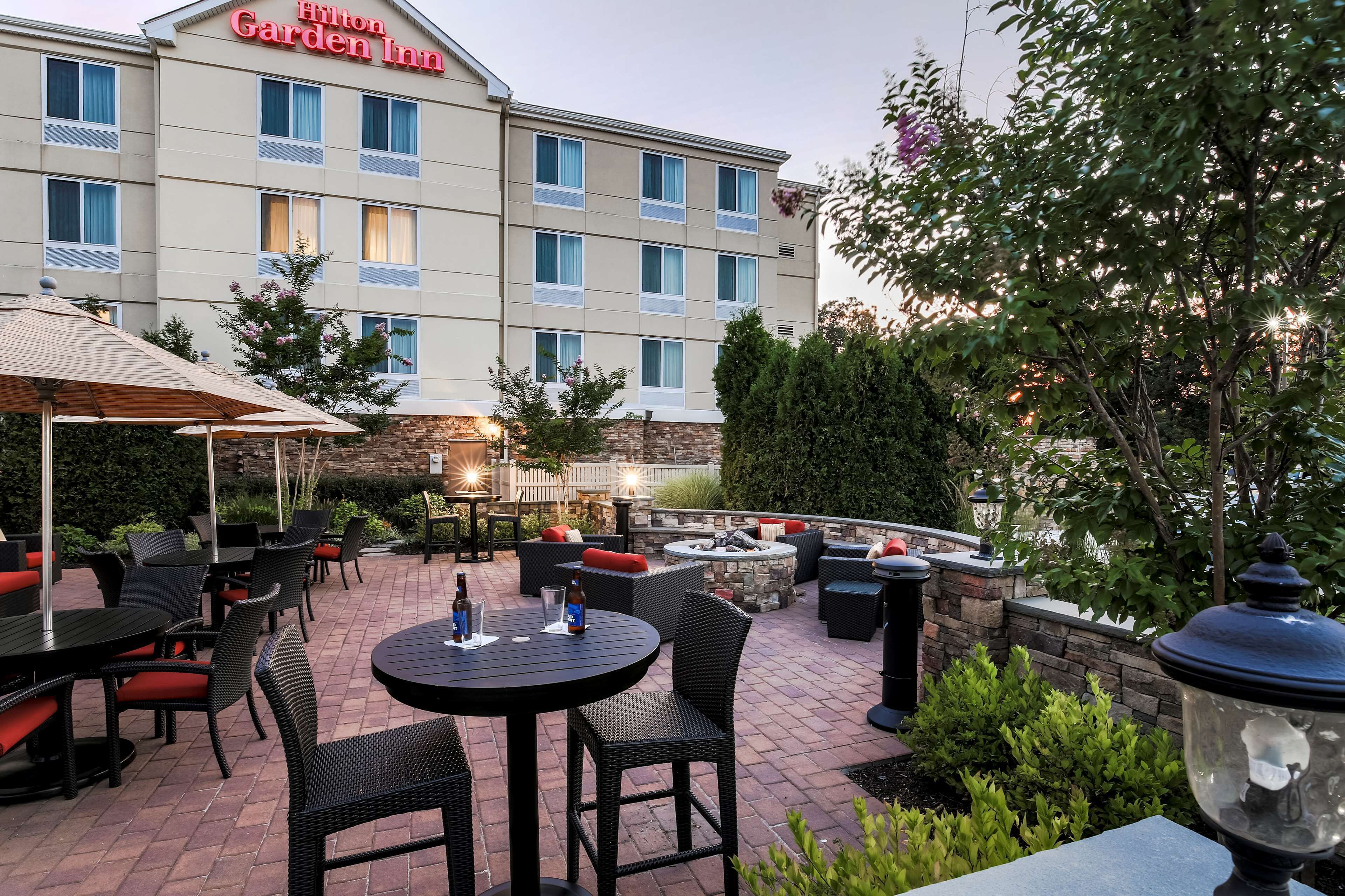 A hotel patio with outdoor seating, a stone wall, and a large building with a sign.