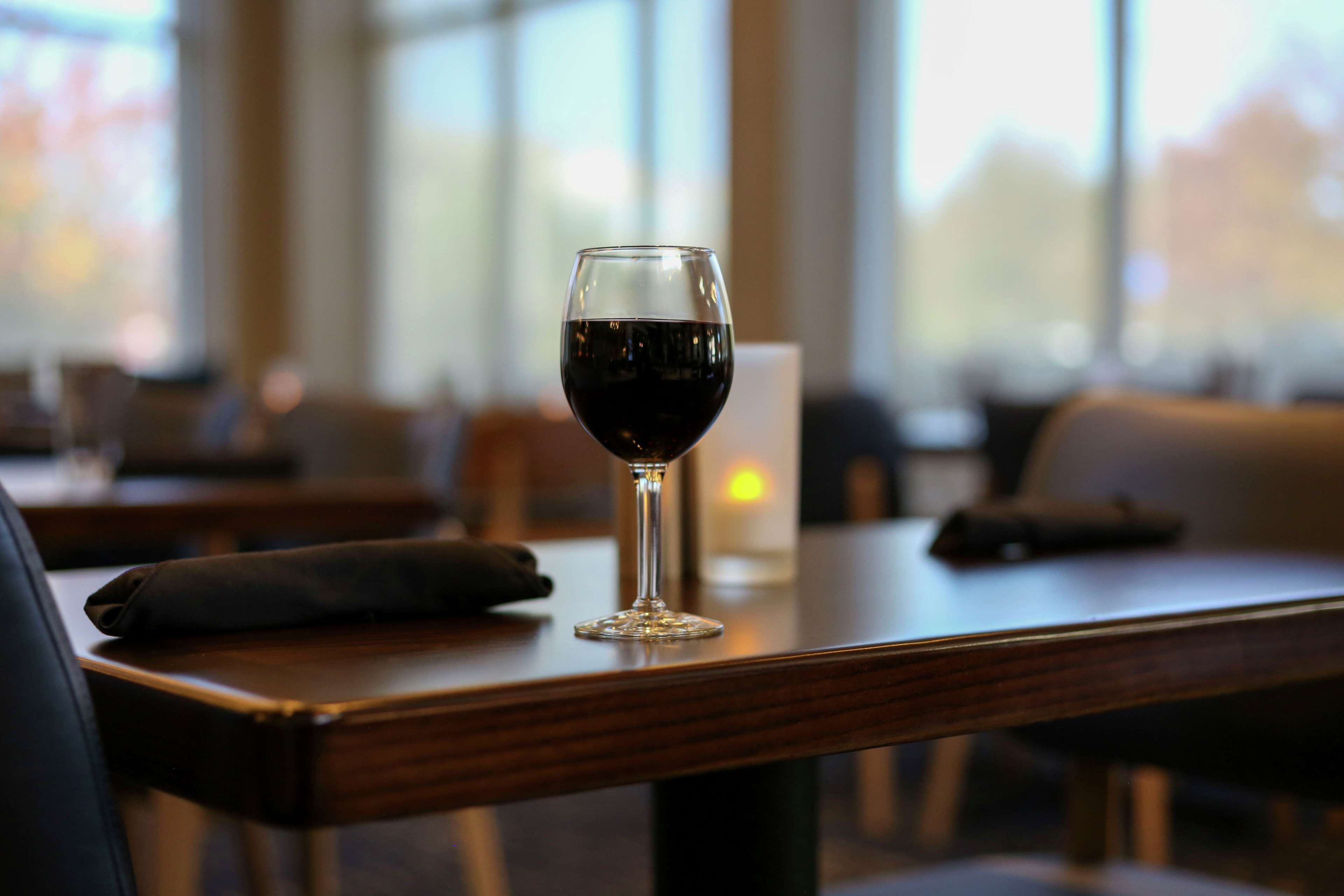 Una copa de vino tinto sobre una mesa de madera en un restaurante.