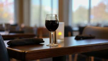 Una copa de vino tinto sobre una mesa de madera en un restaurante.
