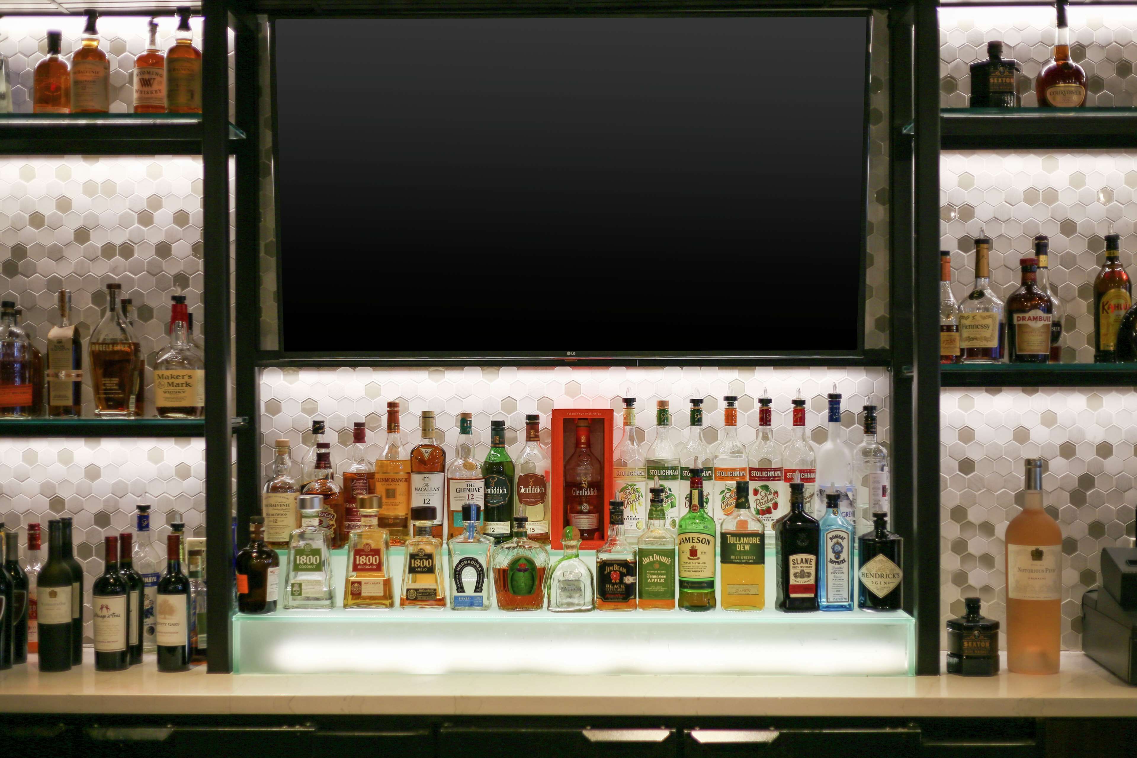 Uma área de bar com prateleiras cheias de garrafas de bebidas diversas.
