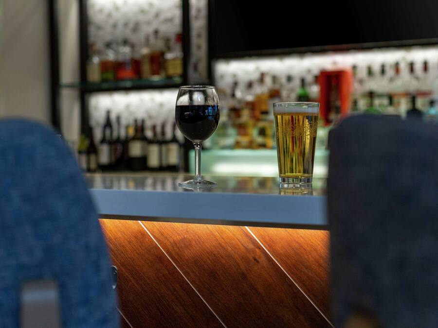 A bar area with a glass of red wine and a glass of beer on the counter.