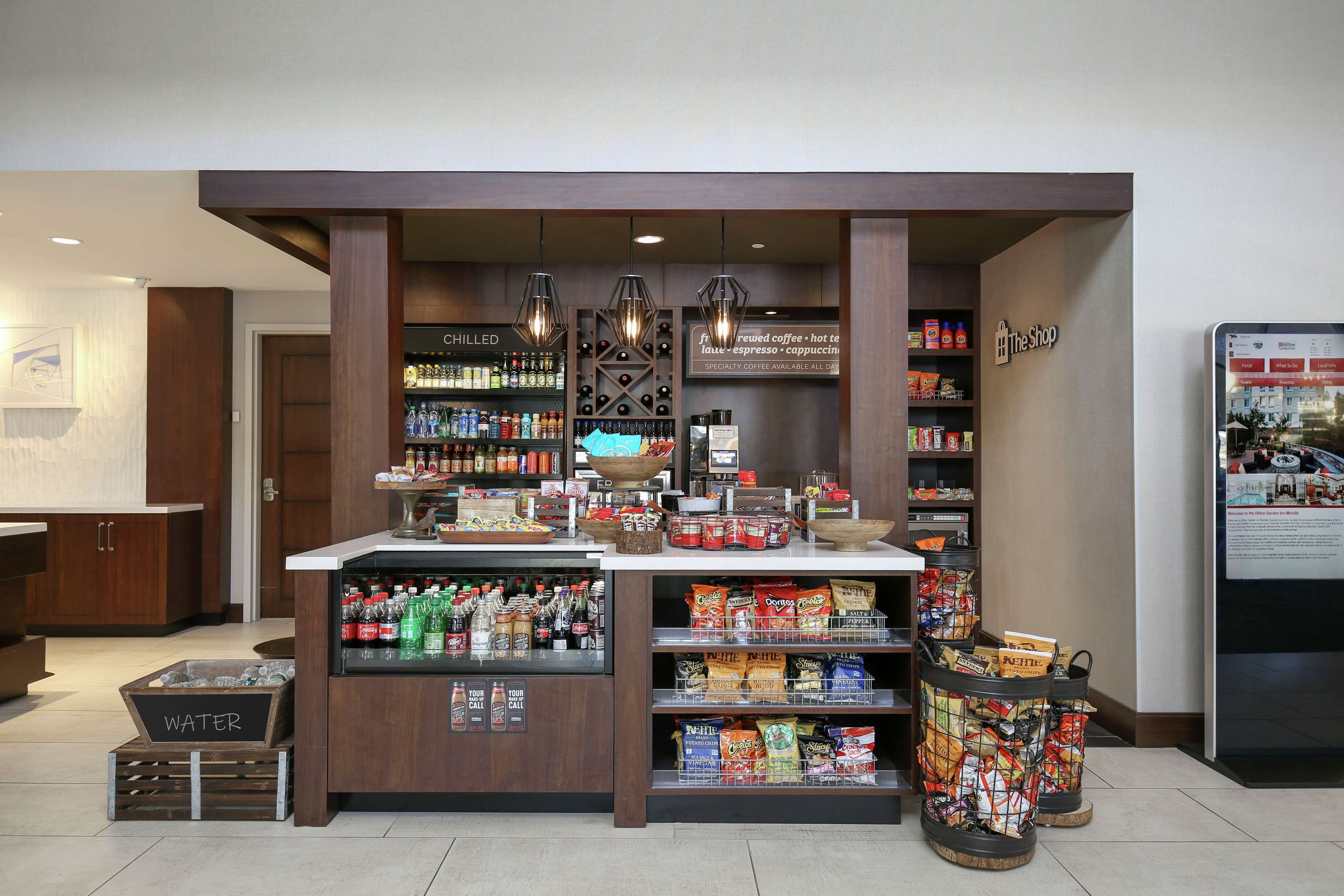 Una cafetería con una variedad de bebidas y aperitivos, incluyendo agua embotellada y café.